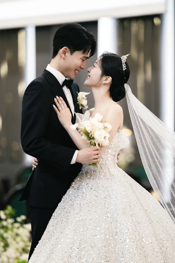 야외 테라스 기둥 배경, 이마를 맞대고 부케 사이로 웃는 신랑신부