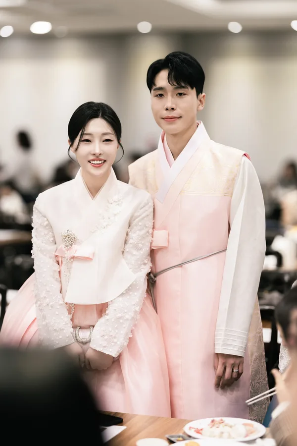 연분홍 한복을 입고 피로연장에서 다정하게 선 신랑신부 상반신컷